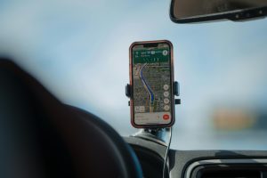 A smartphone screen displaying various travel apps with a scenic road trip background, highlighting apps for navigation, accommodation, and entertainment.